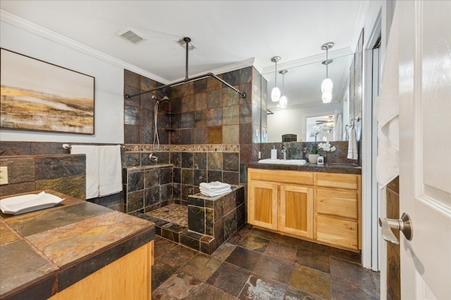 bathroom with vanity, tiled shower, tile patterned floors, tile walls, and crown molding