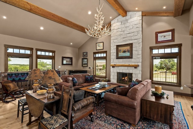 living room with a stone fireplace, a wealth of natural light, light wood-type flooring, and an inviting chandelier