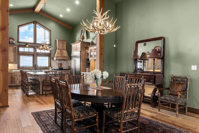 dining space featuring beam ceiling, light hardwood / wood-style floors, a chandelier, and high vaulted ceiling