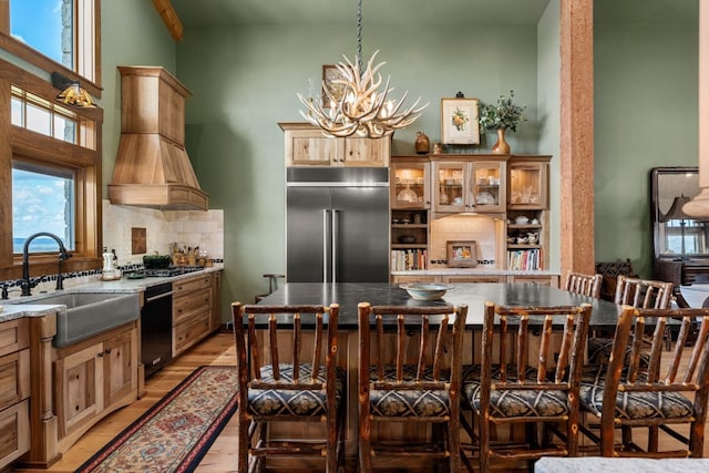 kitchen with custom range hood, stainless steel appliances, sink, a kitchen island, and light hardwood / wood-style flooring