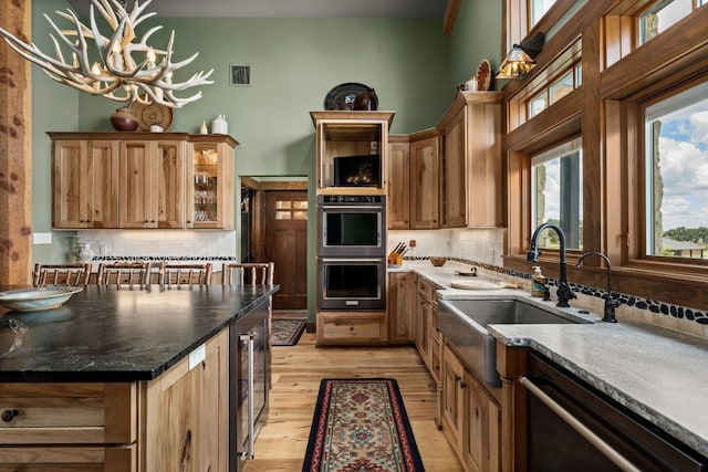 kitchen featuring light hardwood / wood-style flooring, an inviting chandelier, stainless steel appliances, decorative backsplash, and decorative light fixtures