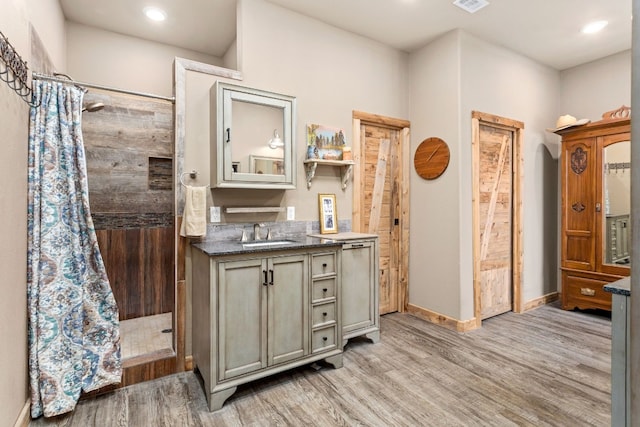 bathroom with recessed lighting, vanity, a shower stall, wood finished floors, and baseboards