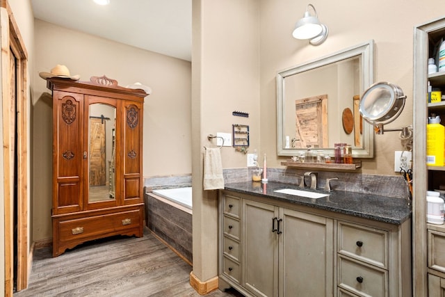 bathroom with vanity, tiled tub, and hardwood / wood-style flooring