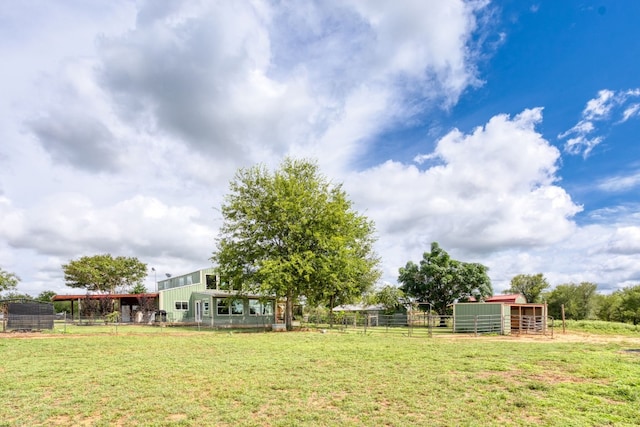 view of yard with a rural view, an exterior structure, an outdoor structure, and fence