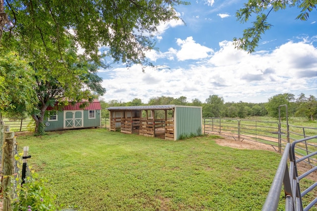 view of yard featuring a rural view, an exterior structure, and an outbuilding