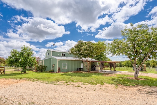 back of house featuring a carport, metal roof, a lawn, and driveway