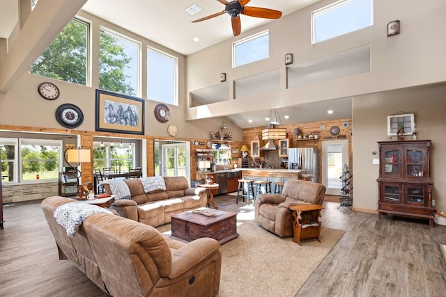 living area featuring visible vents, ceiling fan, a high ceiling, and wood finished floors