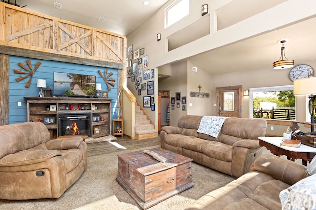 living room featuring stairway, a glass covered fireplace, and a towering ceiling