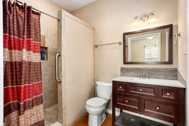 full bathroom with toilet, wood finished floors, vanity, baseboards, and a stall shower