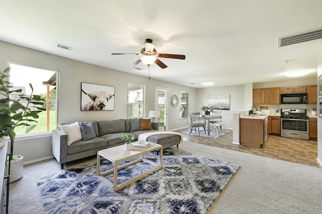 living room featuring sink, ceiling fan, and light carpet