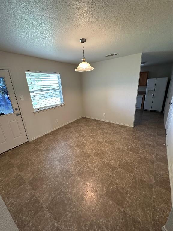 unfurnished dining area featuring a textured ceiling