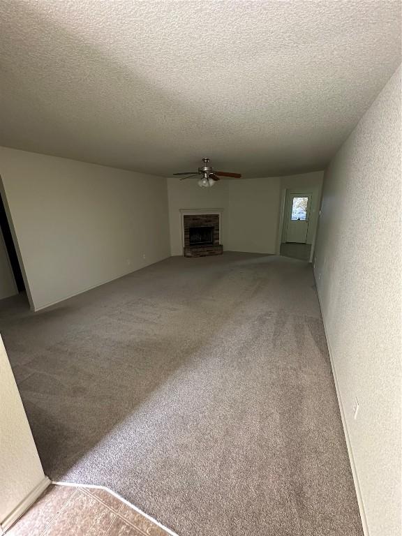 unfurnished living room with ceiling fan, carpet, and a textured ceiling