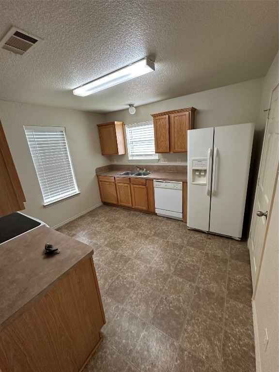 kitchen with tile patterned floors, white appliances, sink, and a textured ceiling