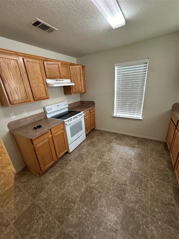 kitchen featuring white range with electric cooktop, a textured ceiling, and dark tile patterned flooring