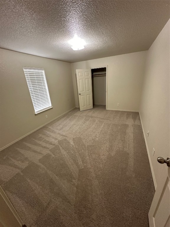 unfurnished bedroom featuring a textured ceiling and light colored carpet