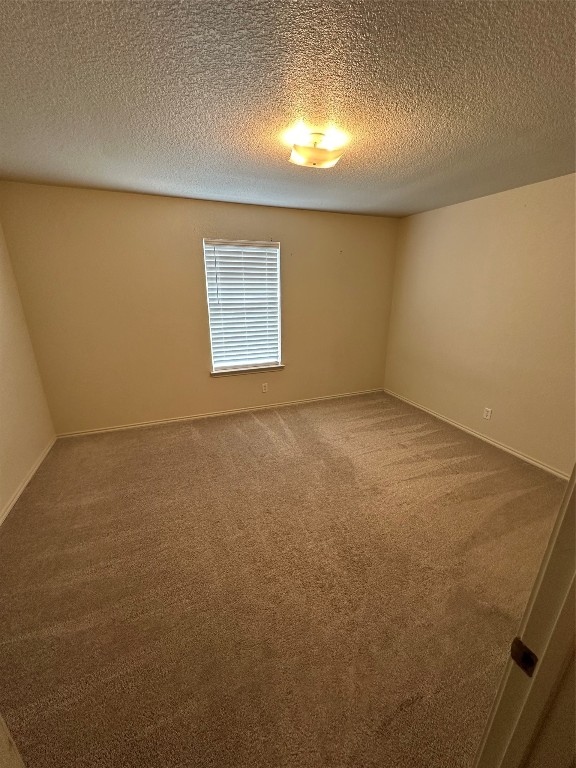 carpeted empty room with a textured ceiling