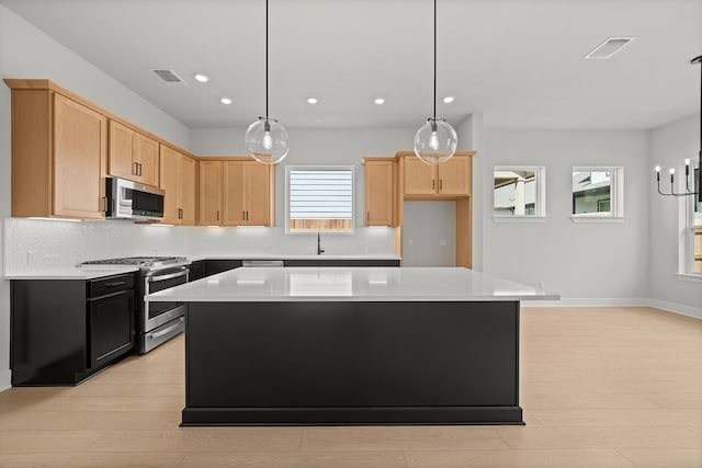 kitchen featuring appliances with stainless steel finishes, light brown cabinetry, a kitchen island, and light hardwood / wood-style floors