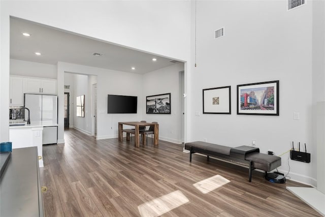 living room with sink, a towering ceiling, and wood-type flooring