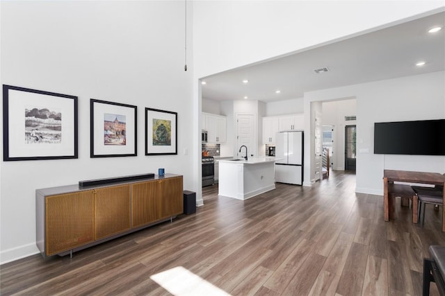 living room featuring sink, dark wood-type flooring, and a high ceiling