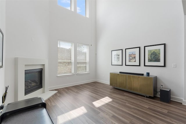 living room with dark wood-type flooring and a towering ceiling