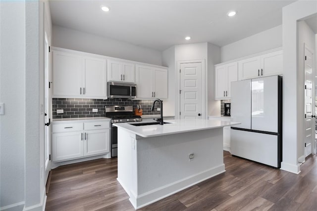 kitchen with stainless steel appliances, white cabinetry, sink, and a center island with sink