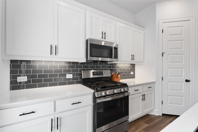 kitchen featuring stainless steel appliances, light countertops, decorative backsplash, dark wood-type flooring, and white cabinetry