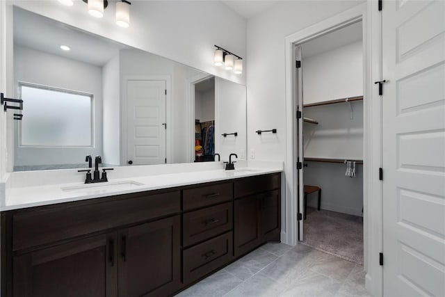 bathroom with double vanity, a spacious closet, and a sink