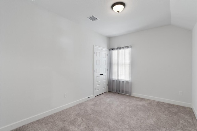 spare room with carpet, visible vents, lofted ceiling, and baseboards