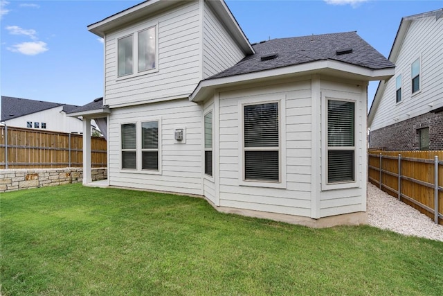 back of property featuring a fenced backyard, a lawn, and roof with shingles