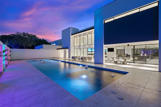 pool at dusk featuring a patio area