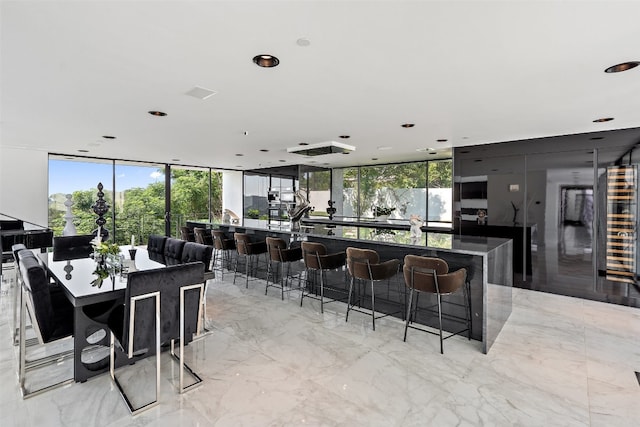 kitchen with a kitchen island, a kitchen breakfast bar, light tile patterned floors, and a wall of windows