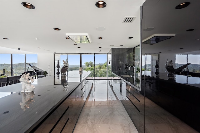 interior space featuring stone counters, expansive windows, light tile patterned floors, and sink