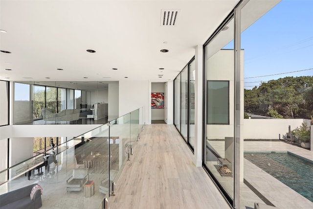 hall with light wood-type flooring and a wall of windows