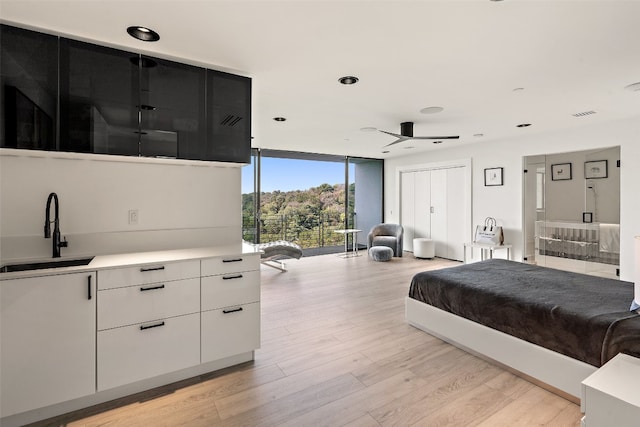 bedroom featuring floor to ceiling windows, ceiling fan, sink, and light hardwood / wood-style floors