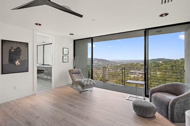 living area with light wood-type flooring, a mountain view, and a wall of windows