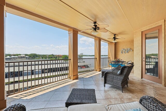 view of patio with a balcony, a water view, and ceiling fan