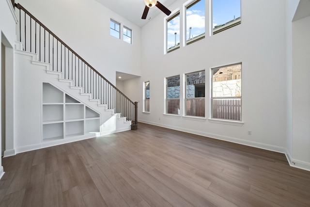 unfurnished living room with a high ceiling, hardwood / wood-style flooring, and ceiling fan