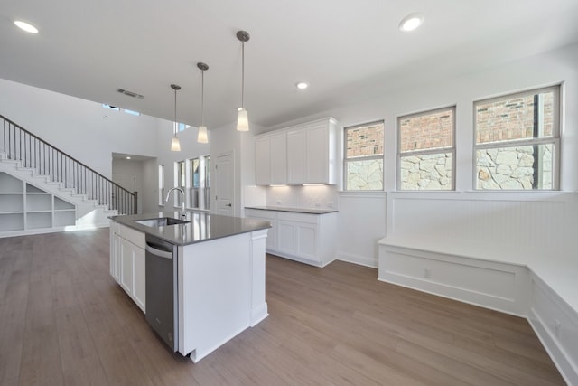 kitchen featuring white cabinetry, sink, dishwasher, dark hardwood / wood-style flooring, and a center island with sink