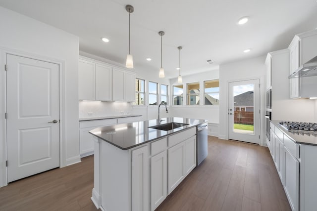 kitchen featuring hanging light fixtures, white cabinetry, a kitchen island with sink, and sink