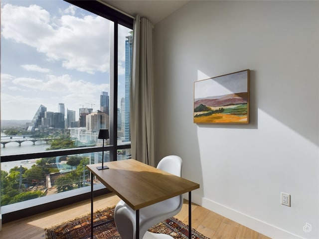 home office with plenty of natural light, expansive windows, wood-type flooring, and a water view