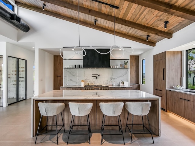 kitchen featuring beam ceiling, a breakfast bar area, light tile patterned floors, a center island, and wood ceiling