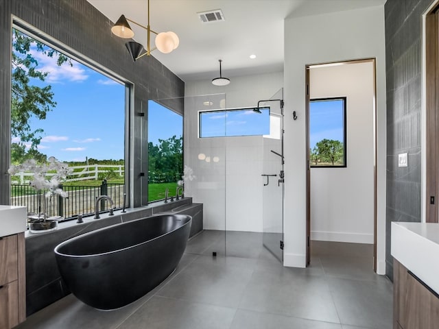 bathroom featuring tile patterned flooring, a bathing tub, vanity, and plenty of natural light