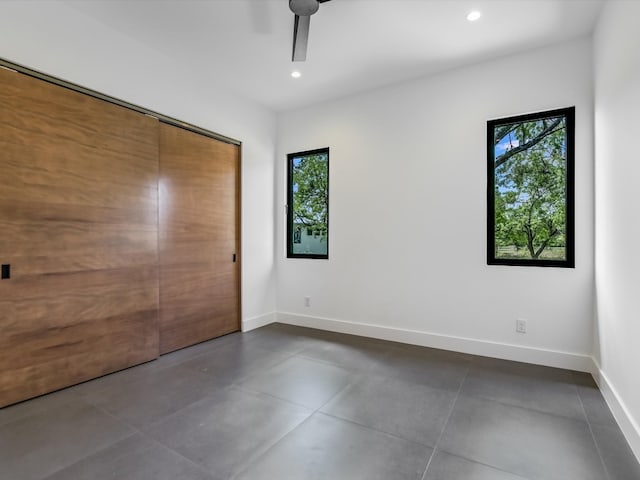 unfurnished bedroom featuring dark tile patterned floors, a closet, and ceiling fan