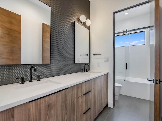 full bathroom featuring tile patterned flooring, dual bowl vanity, backsplash, toilet, and combined bath / shower with glass door