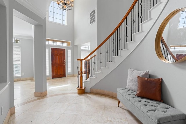 tiled entryway with a high ceiling, ornamental molding, and an inviting chandelier