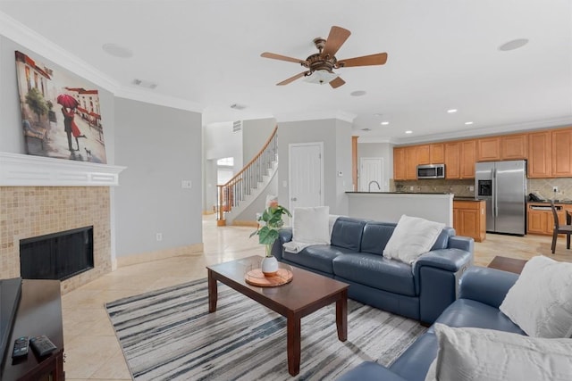 tiled living room featuring crown molding, a fireplace, and ceiling fan