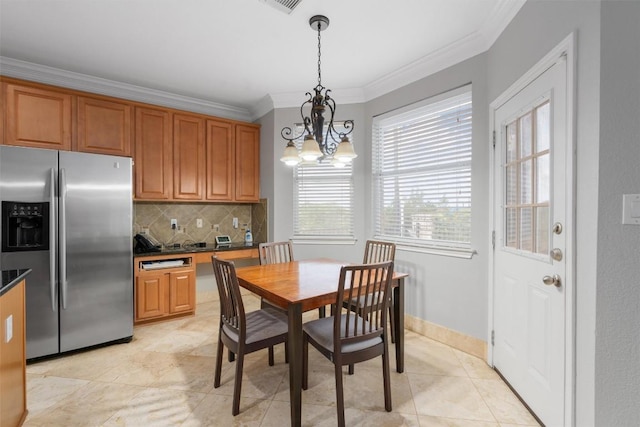 tiled dining room featuring ornamental molding and a chandelier