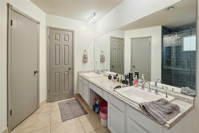 bathroom featuring tile patterned floors, walk in shower, and dual bowl vanity