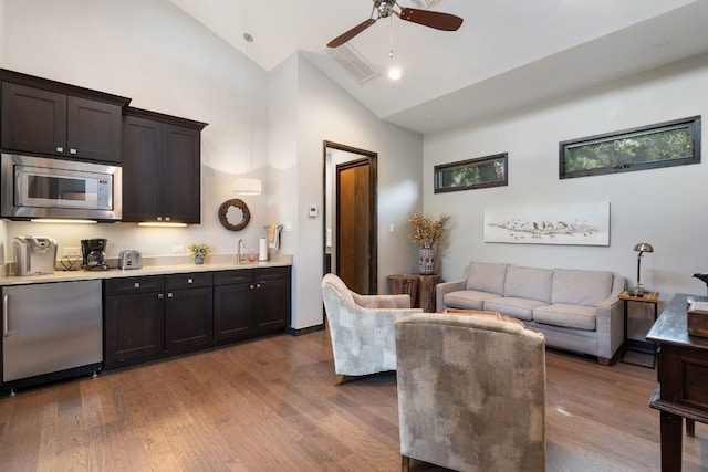 living area featuring high vaulted ceiling, a ceiling fan, visible vents, and wood finished floors