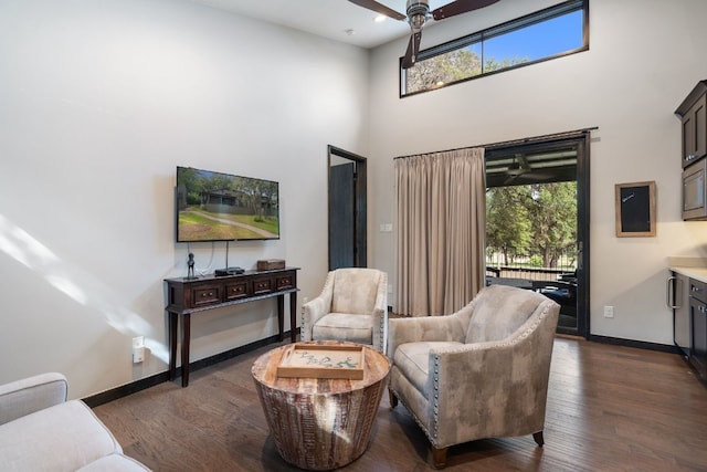 living room featuring dark hardwood / wood-style flooring, a towering ceiling, and ceiling fan